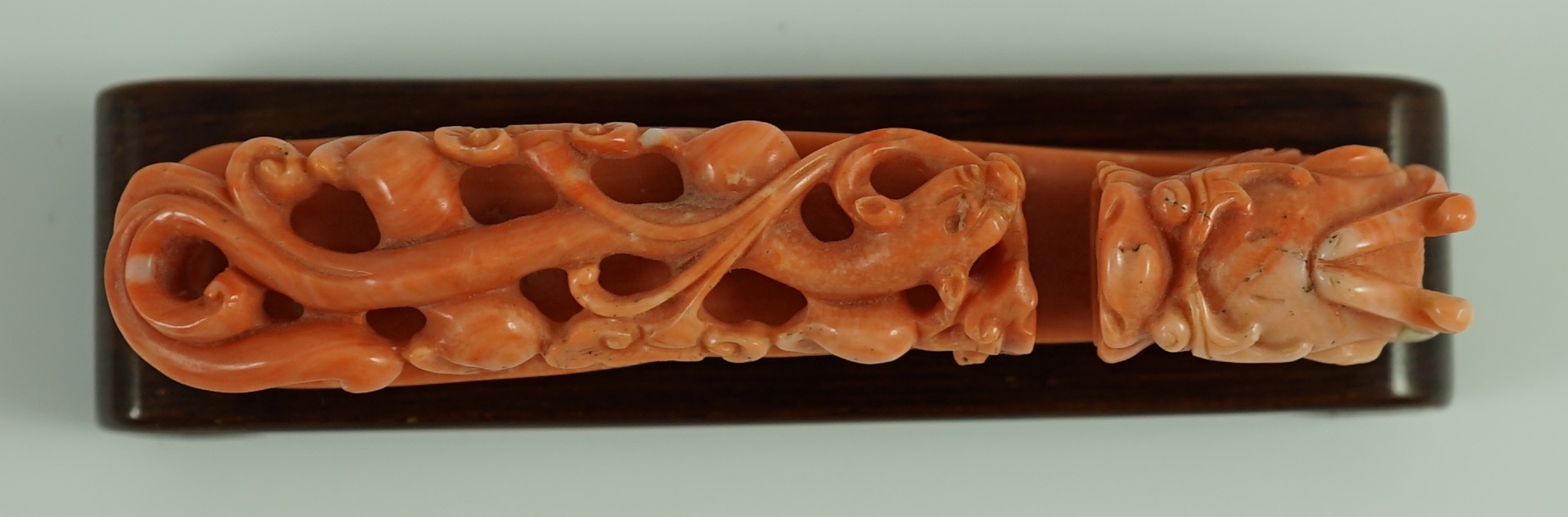 A rare Chinese coral 'dragon' belt hook 18th/19th century, 9.2 cm long, small loss to dragon horn, wood stand